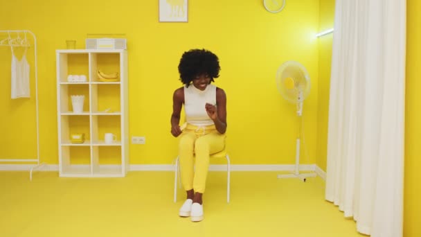 Женщина сидит в желтой комнате и танцует — стоковое видео