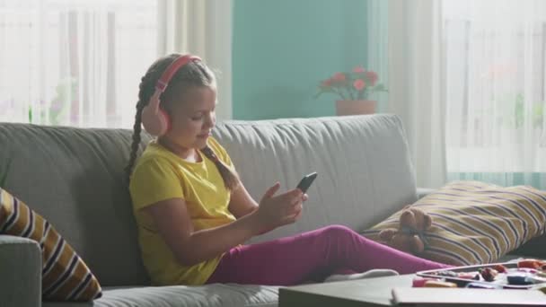 Niña pequeña está utilizando el teléfono móvil para entretener — Vídeos de Stock