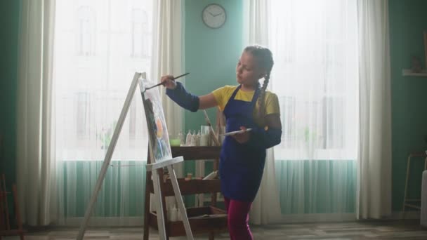Écolière est peinture et regarder caméra — Video