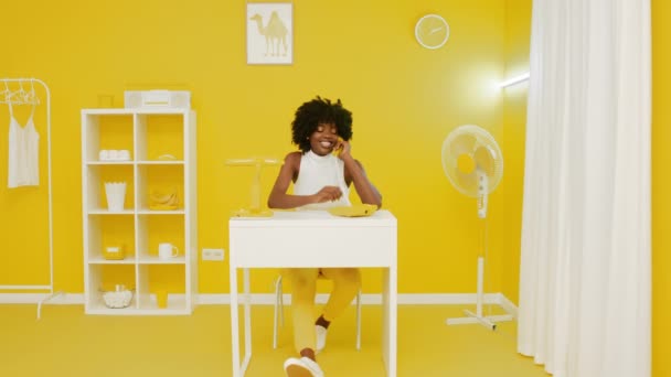 Счастливая женщина разговаривает по телефону в желтом офисе — стоковое видео