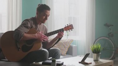 Genç adam gitar çalmayı öğreniyor.