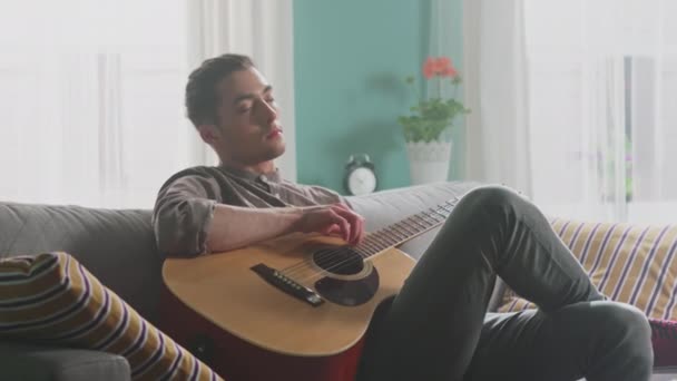 Молодой человек любит играть на гитаре — стоковое видео