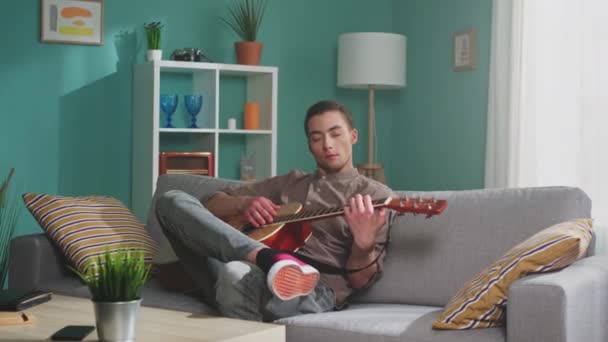 Jeune homme joue de la guitare à la maison — Video