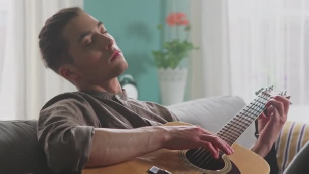 Молодой человек медитирует, играя на гитаре — стоковое видео