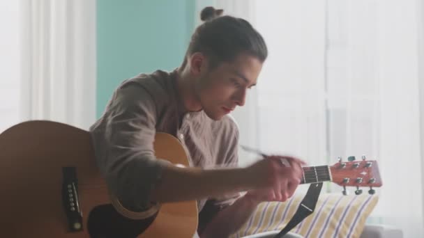 Молодой человек сочиняет музыку дома — стоковое видео