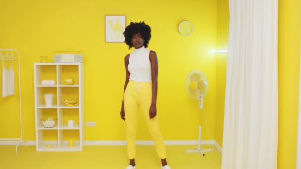 Portret czarnej kobiety stojącej w wibrującym żółtym pokoju — Wideo stockowe