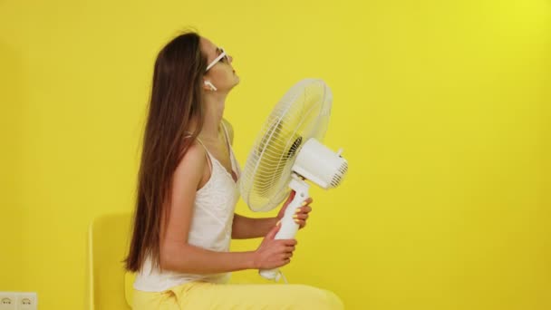 長い髪を持つセクシーな女性は電気ファンと一緒にポーズをとっています — ストック動画