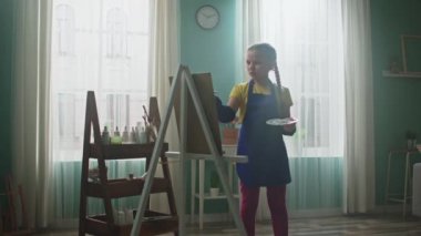 Çalışkan kız tuvale resim yapıyor.