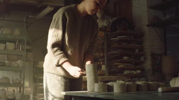 Vrouw pottenbakker is snijden af klei stukken — Stockvideo