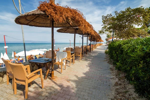 Sunny street café en la costa del mar Mediterráneo en el pueblo de Hanioti, Halkidiki, Grecia . — Foto de Stock