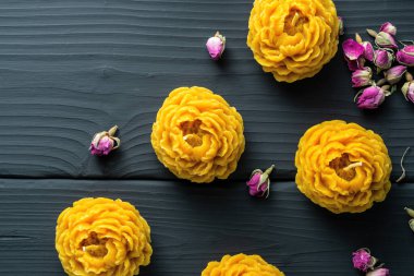 Balmumundan yapılma dekoratif çiçek mumları. İçi bal aromalı ve koyu ahşap arka planda bir gelenek..