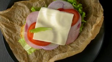 Lezzetli sandviçler koyu taştan bir zemin üzerinde döner, düz görünüm.