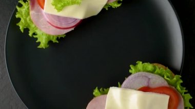 Lezzetli sandviçler koyu taştan bir zemin üzerinde döner, düz görünüm.