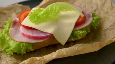 Lezzetli sandviçler koyu taştan bir zemin üzerinde döner, düz görünüm.