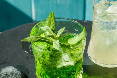 Geleneksel buzlu yaz kokteyli. Mavi arka planda köpüklü su ve nane şekeri..