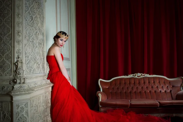 Hermosa chica en vestido largo rojo y en corona real — Foto de Stock