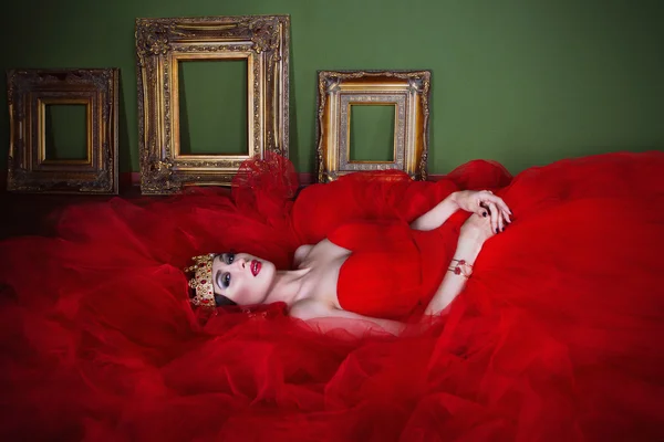 Bella ragazza in abito rosso lungo e in corona reale posa — Foto Stock