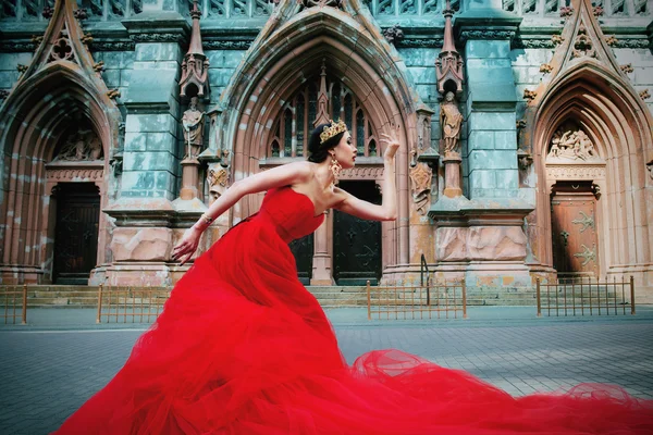 Hermosa chica en vestido largo rojo y en real — Foto de Stock