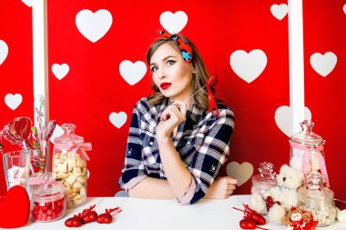 Pin-up tarzı kırmızı beyaz kalpleri arka plan ile güzel ve genç birbayan