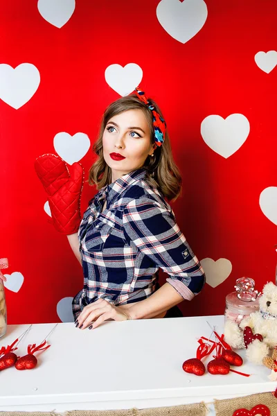 Hermosa mujer joven en estilo pin-up en rojo con fondo de corazones blancos —  Fotos de Stock