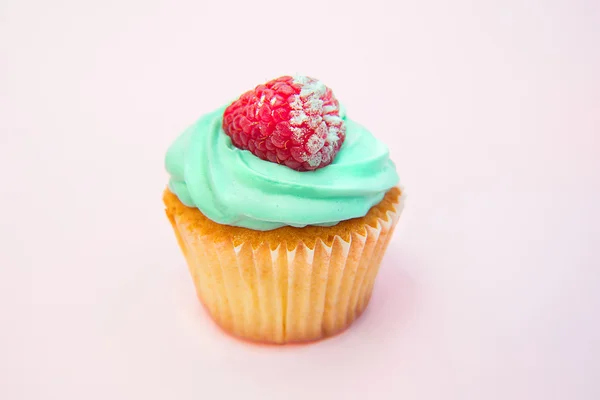 Cupcakes con crema de mantequilla y vainilla con frambuesa sobre fondo rosa —  Fotos de Stock