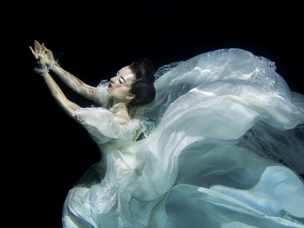 Niña en vestido de lujo blanco largo bajo el agua en el fondo negro — Foto de Stock