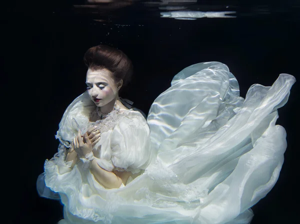 Ung flicka i långa vita lyx klänning under vattnet på den svarta bakgrunden — Stockfoto