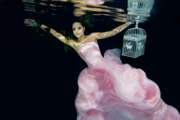 Vrouw in lange roze jurk onderwater — Stockfoto