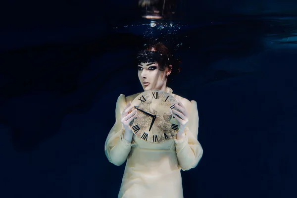 Fille avec horloge dans ses mains en voile noir sous l'eau — Photo