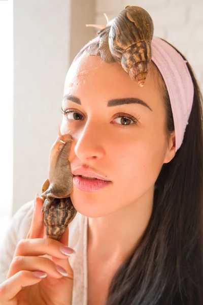 portrait of young darkhaired woman with snails achatina giant on her face