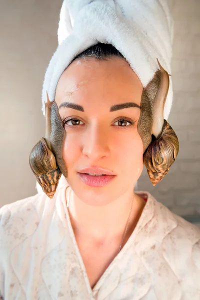 Портрет молодой темноволосой женщины с улитками ачатинского гиганта на лице — стоковое фото