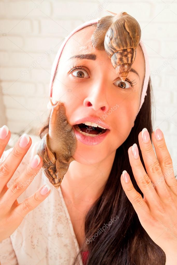 portrait of young afraid darkhaired woman with snails achatina giant on her face