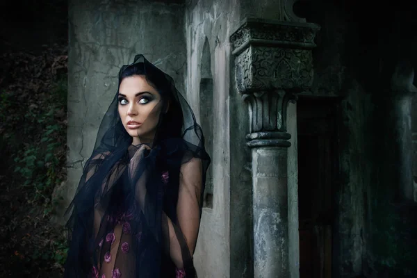 Retrato de uma menina em um vestido rosa e um véu preto perto do túmulo no cemitério — Fotografia de Stock