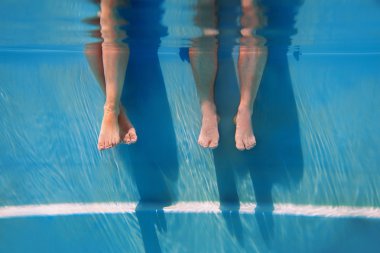 adults legs in sunny day in the swimming pool underwater clipart