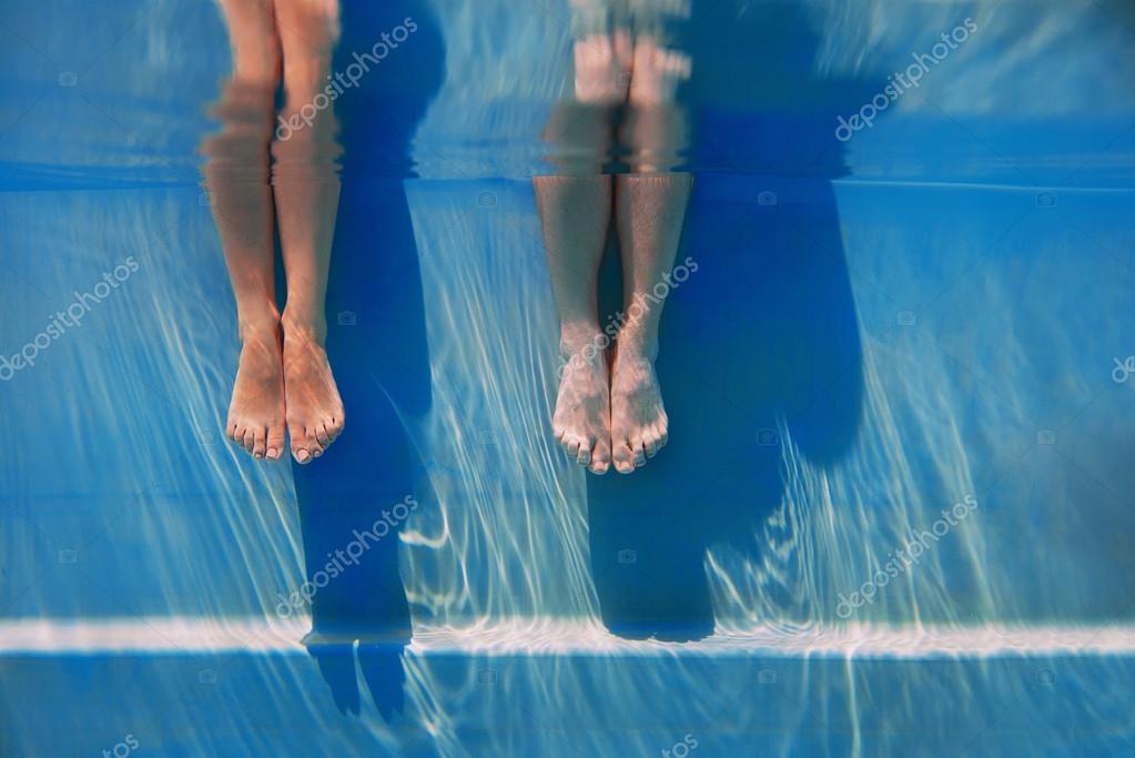 Adults legs in sunny day in the swimming pool underwater — Stock Photo