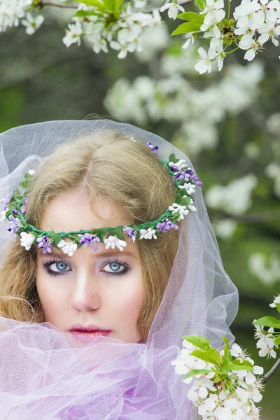 Hermosa chica rubia joven en los árboles en flor en primavera —  Fotos de Stock