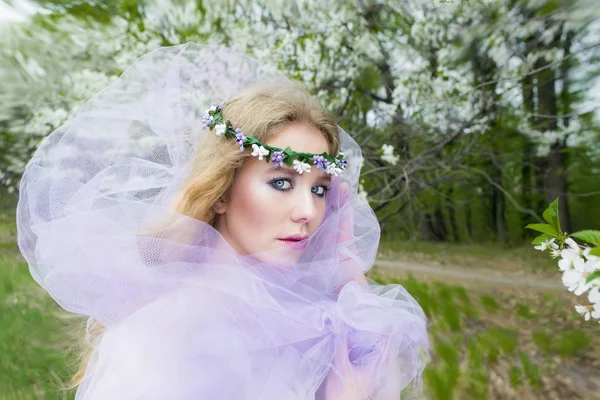 Bela jovem loira menina em árvores florescentes na primavera — Fotografia de Stock