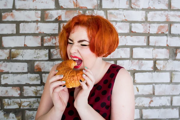 Ler rödhårig flicka i pin-up stil med bröd — Stockfoto