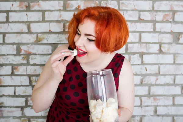 Ler rödhårig flicka i pin-up stil äta marshmallows — Stockfoto