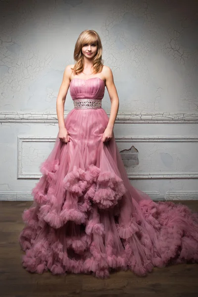 Retrato de menina bonita jovem em vestido rosa longo na sala branca — Fotografia de Stock