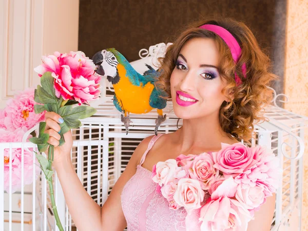 Portret van jonge mooie vrouw in kleurrijke jurk met bloemen het in stijl van de pop met ara op haar shoulderon — Stockfoto
