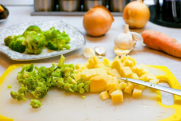 Kochen vegetarische Suppe aus Kichererbsen und Brokkoli. Messer, Brokkoli vorhanden. Möhren, Zwiebeln und Kartoffeln auf einem Brett — Stockfoto