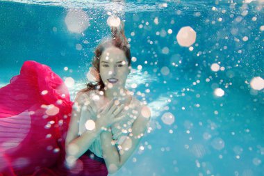 Genç gülümseyen güzel yüzme havuzunda sualtı elbiseli kadın beyaz