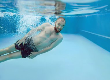 bearded man dives underwater  