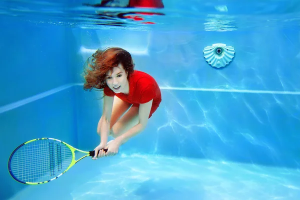 Mooi meisje tennissen onder water in het zwembad — Stockfoto