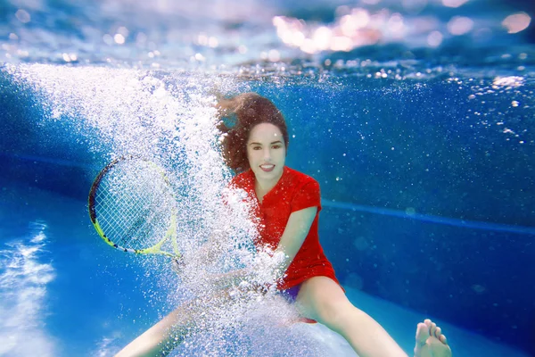 Mooi meisje tennissen onder water in het zwembad — Stockfoto