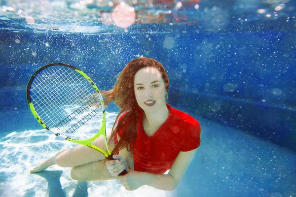 Junges schönes Mädchen spielt Tennis unter Wasser im Schwimmbad — Stockfoto