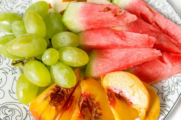 Персик, белый виноград, арбуз и дыня на тарелке — стоковое фото