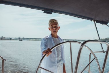 Beyaz tişörtlü, yelkenli yatlı, ciddi sarışın çocuk. Eğitim, dersler, öğrenim, beceriler, büyüme kavramı