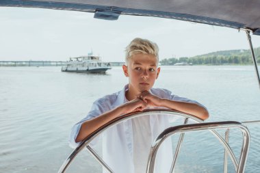 Beyaz tişörtlü, yelkenli yatlı, ciddi sarışın çocuk. Eğitim, dersler, öğrenim, beceriler, büyüme kavramı